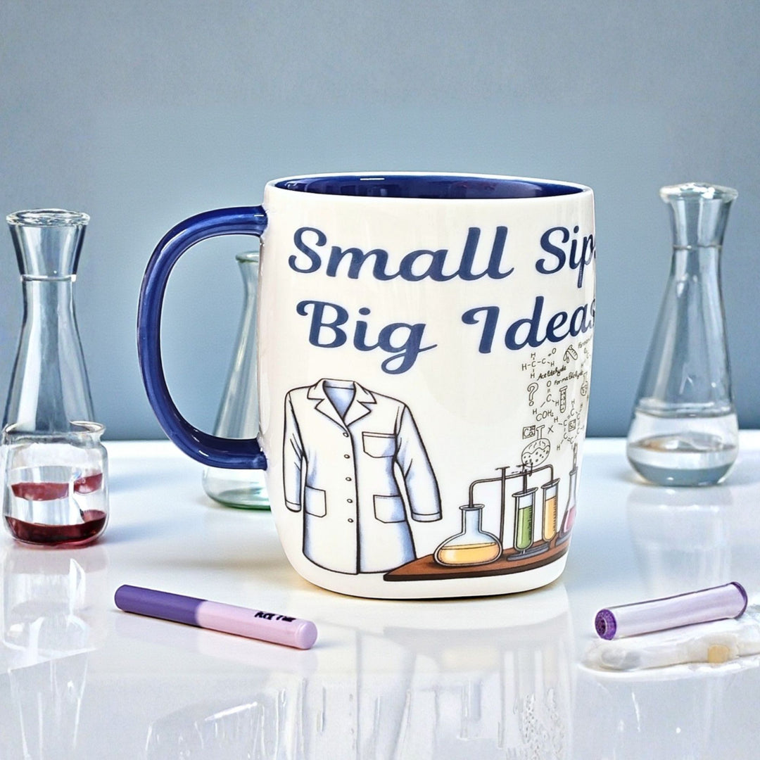 Ceramic Mug with 'Small Sips Big Ideas' text and scientist design on a white surface with lab-themed items.