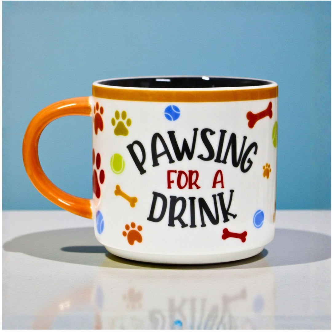 Ceramic Mug with 'Pawsing for a Drink' text and colorful dog-themed illustration .
