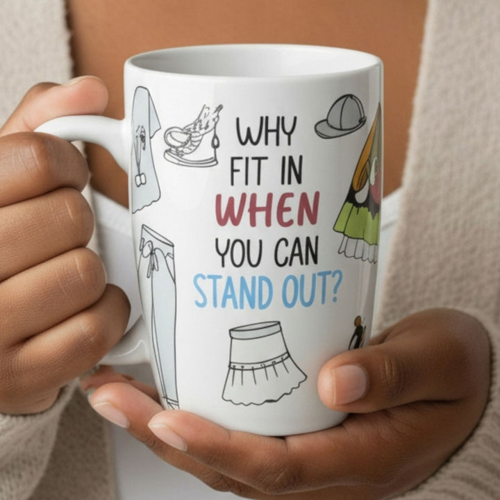 Person holding a mug with a motivational quote "Why Fit In When You Can Stand Out" and sketch illustrations of clothing.