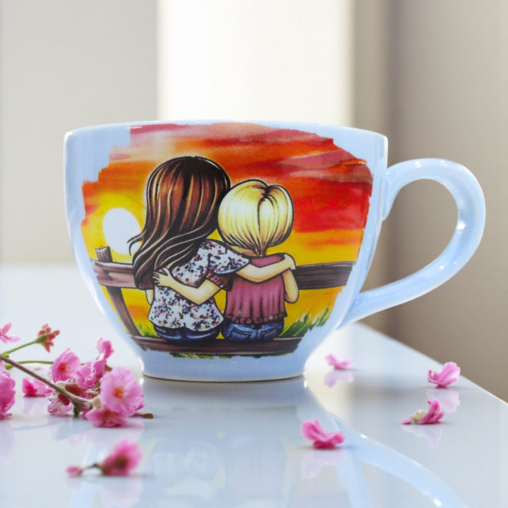 Light blue ceramic mug with a design of two children hugging at sunset